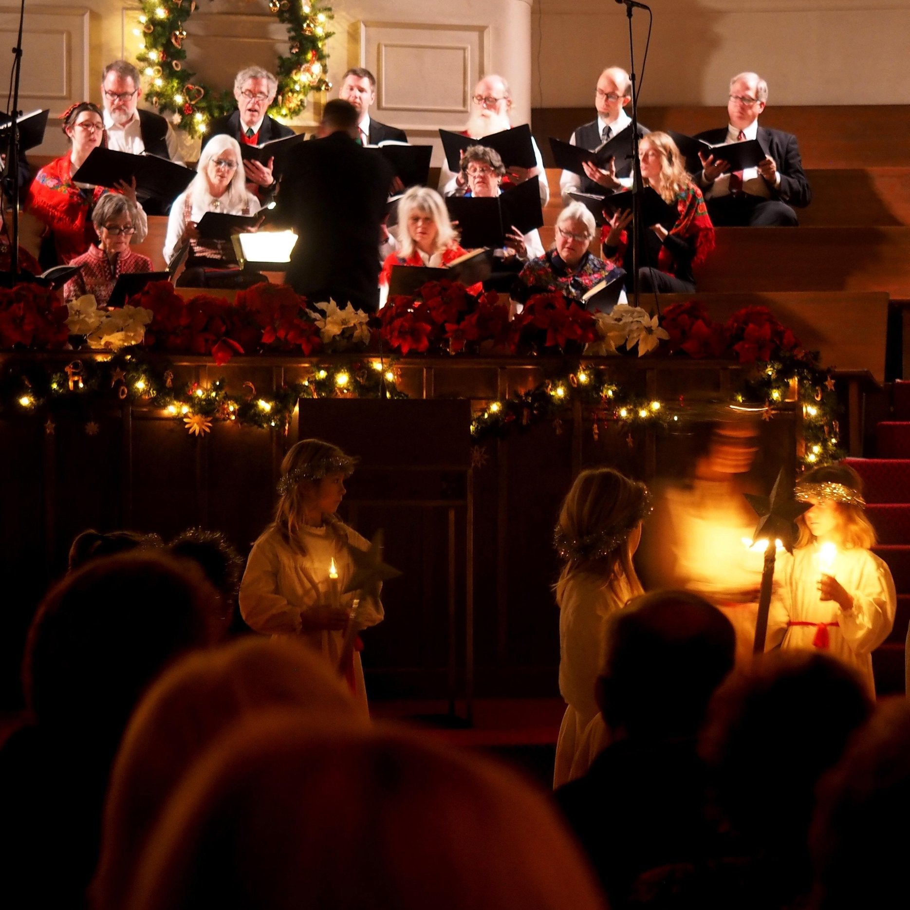 Congregation members worshiping and watching a choir perform in a church